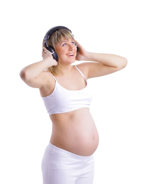 Glad gravid kvinna lyssnar musik i hörlurar isolerad på vit — Stockfoto