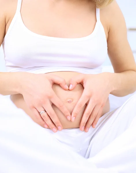 Mujer embarazada haciendo forma de corazón con las manos sobre su estómago — Foto de Stock