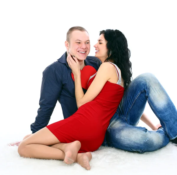 Bonito jovem casal de amor sentado no chão com um grande coração vermelho — Fotografia de Stock