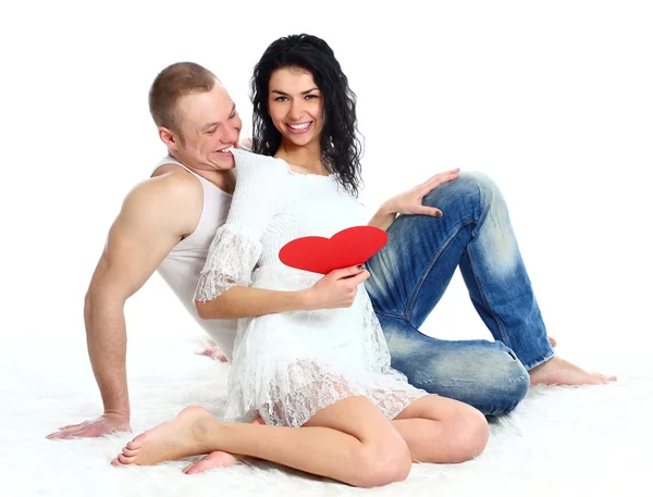 Felice giovane coppia adulta con il cuore rosso sul pavimento, abbracciando e ridendo — Foto Stock