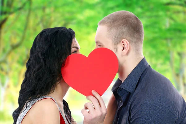 Happy couple with heart kissing outdoors — Stock Photo, Image