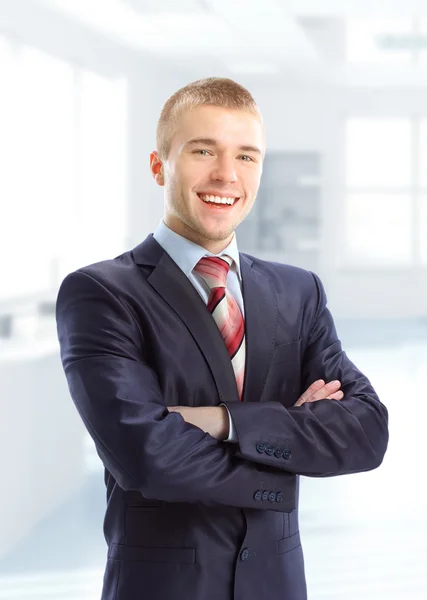 Молодой улыбающийся бизнесмен, стоящий в своем смертельном офисе — стоковое фото