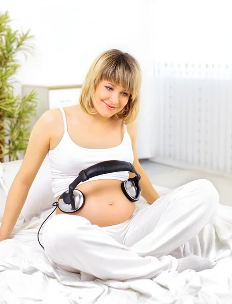 Pregnant woman with headphones on bump — Stock Photo, Image