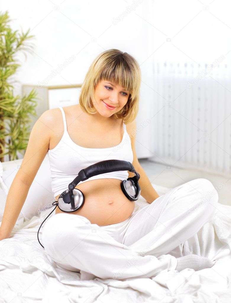 Pregnant woman with headphones on bump