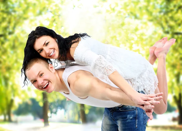 Älskande par njuter av tillsammans medan piggyback rida utomhus — Stockfoto