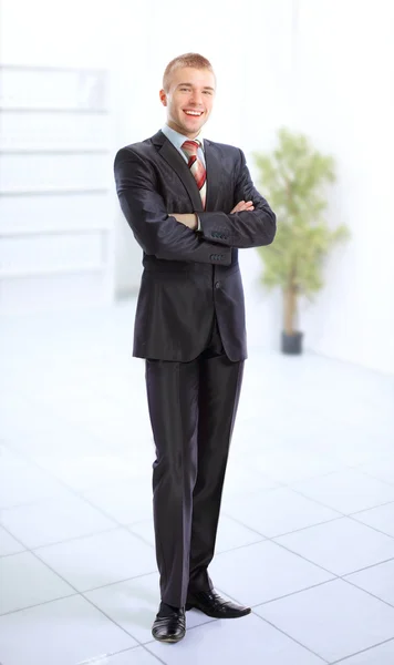 Молодий усміхнений бізнесмен стоїть в легкому і темному діловому залі . — стокове фото