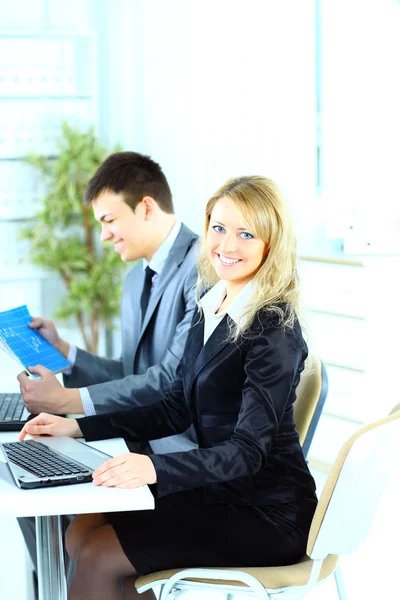 Nette junge Geschäftsfrau lächelt bei einem Treffen mit Kollegen im Hintergrund — Stockfoto