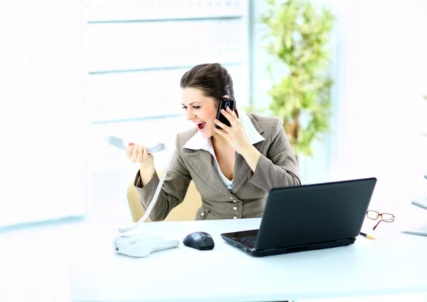 Γυναίκα φωνάζει στο τηλέφωνο μπροστά από έναν υπολογιστή lap-top — Φωτογραφία Αρχείου