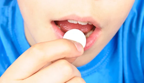 The child puts the pill into his mouth — Stock Photo, Image