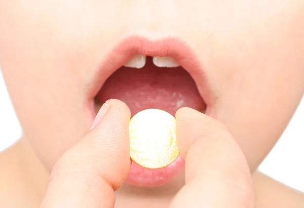 El niño se pone la píldora en la boca. — Foto de Stock