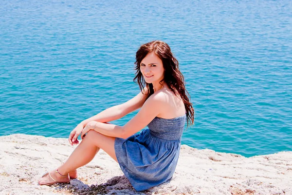 Flickan på klipporna mot havet — Stockfoto