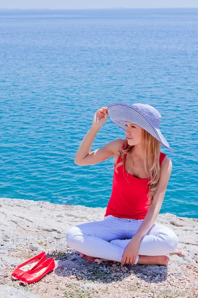 A menina nas rochas contra o mar — Fotografia de Stock