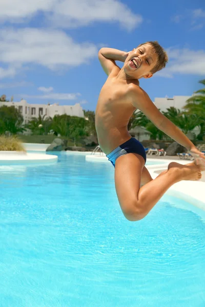 Boy jumping into the pool smiling — Stock Photo, Image