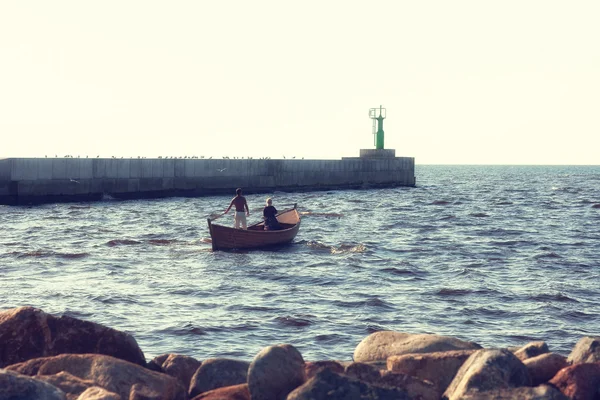 Paar fährt mit Boot am Leuchtturm aufs Meer — Stockfoto