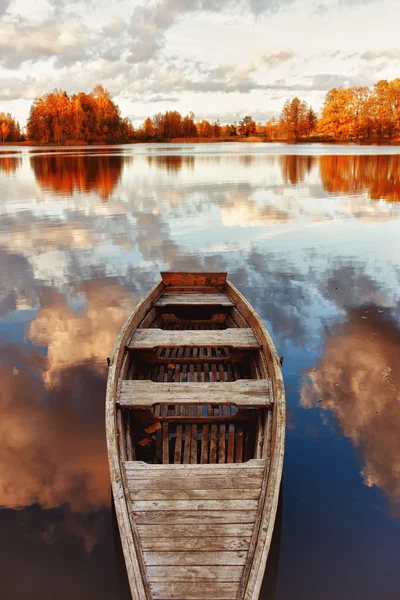 stock image Wooden boat in the lake with the reflection of clouds