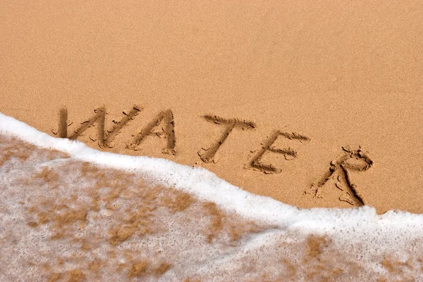 Надпись вода на песке на пляже — стоковое фото