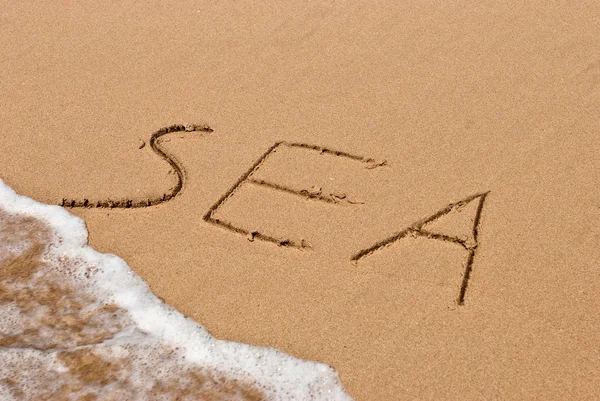 Havet handskrivna i sanden på en strand — Stockfoto