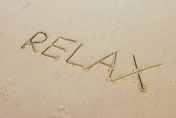 Расслабьте рукописную надпись на песке на пляже
