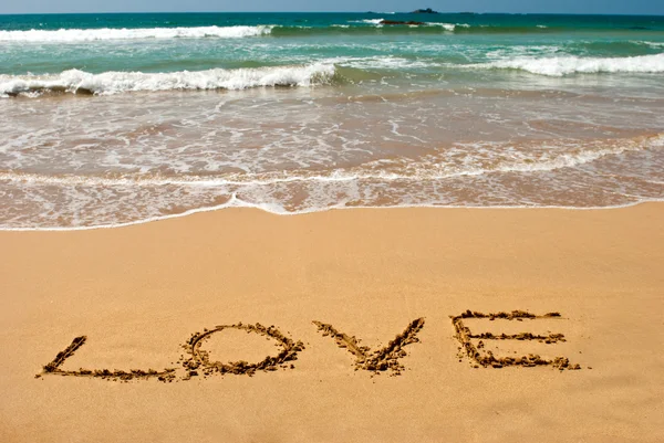 Inschrift "Liebe" auf nassem goldenen Sand am Strand — Stockfoto