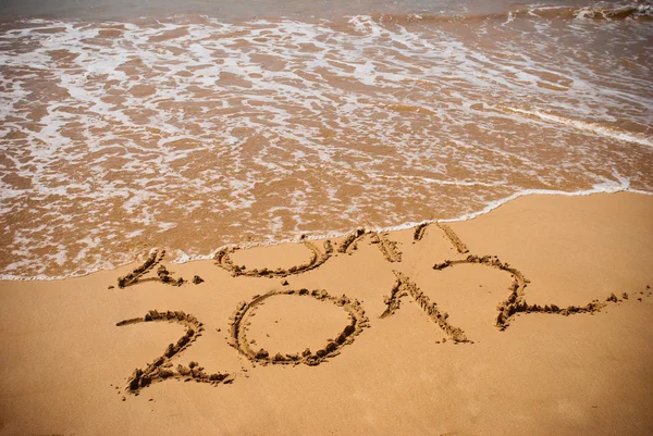 Inscrição 2011 e 2012 em uma areia de praia — Fotografia de Stock