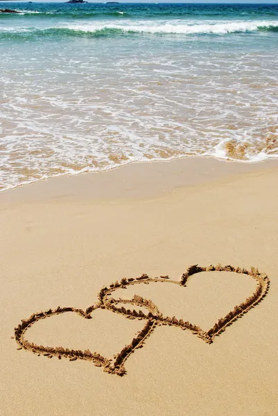 Iki kalp ıslak altın plaj kum üzerinde çizim — Stok fotoğraf