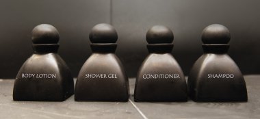 Body lotion, shampoo, shower gel and conditioner in black ceramic bottles clipart