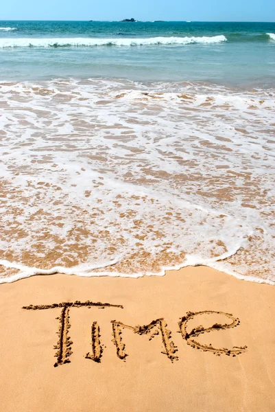 stock image Inscription time on wet golden beach sand in front of the ocean.