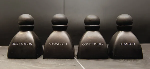 Lotion corporelle, shampooing, gel douche et revitalisant dans des bouteilles en céramique noire — Photo