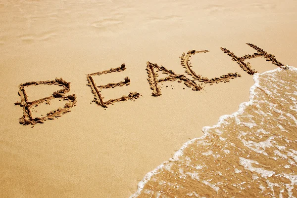 Aufschrift "Strand" auf dem Sand am Strand — Stockfoto