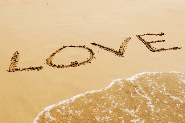 The inscription on the sand near the sea and the waves - LOVE. Royalty Free Stock Photos