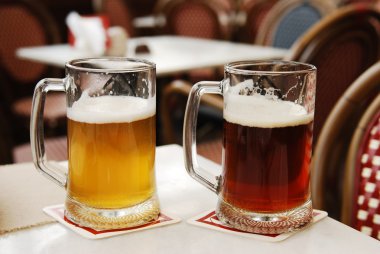 Glasses with light and dark beer in a cafe clipart