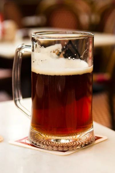 Муг темного пива крупним планом на столі в кафе — стокове фото