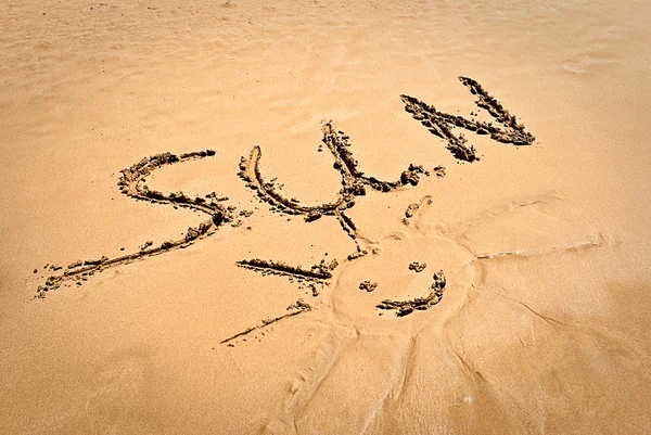 Concept photo of smiling sun with discription "SUN" on the beach sand — Stock Photo, Image