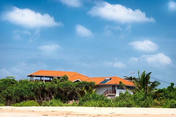 Casa al mare con pannelli solari e vegetazione tropicale con il cielo blu — Foto Stock
