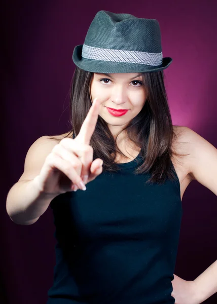 Молодая красивая женщина в стильной шляпе показывает пальцем — стоковое фото