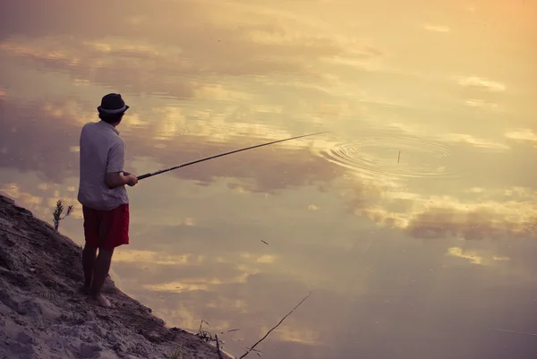 Een man die vissen in de hemel reflectie — Stockfoto
