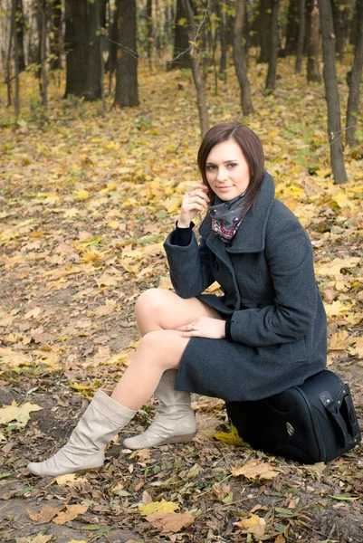 Hermosa joven sentada en la maleta en el bosque —  Fotos de Stock