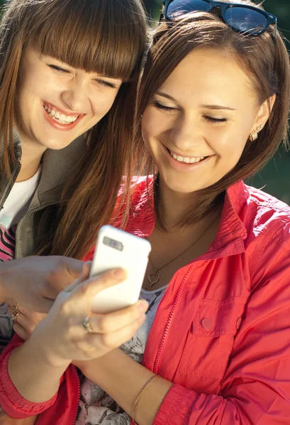 Två glada tjejer med mobiltelefon — Stockfoto