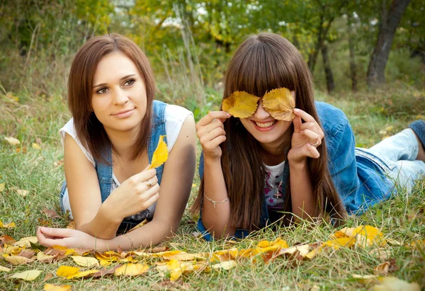 Two girls joking with yellow leaves — Stock Photo, Image