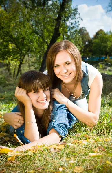 Zwei Mädchen liegen in Herbstblättern — Stockfoto