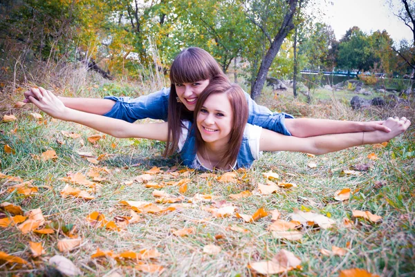 Two happy girls lying in autumn leaves — Stock Photo, Image