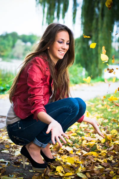 Szczęśliwa kobieta gra z żółtymi liśćmi — Zdjęcie stockowe