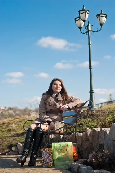 A bevásárló szatyrok padon ülő nő — Stock Fotó