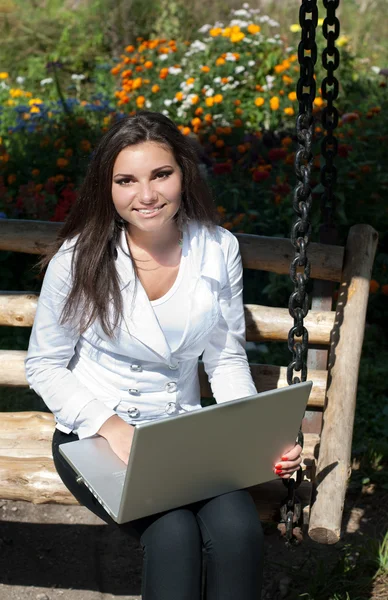 Jonge vrouw met laptop op houten schommel — Stockfoto