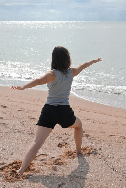Jeune femme faisant des exercices de yoga sur un rivage — Photo