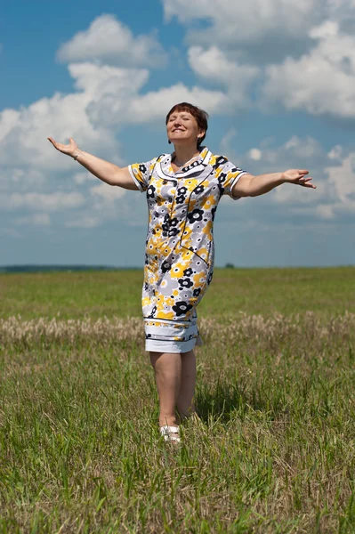 Heureuse femme mature debout dans le champ sous le ciel bleu — Photo