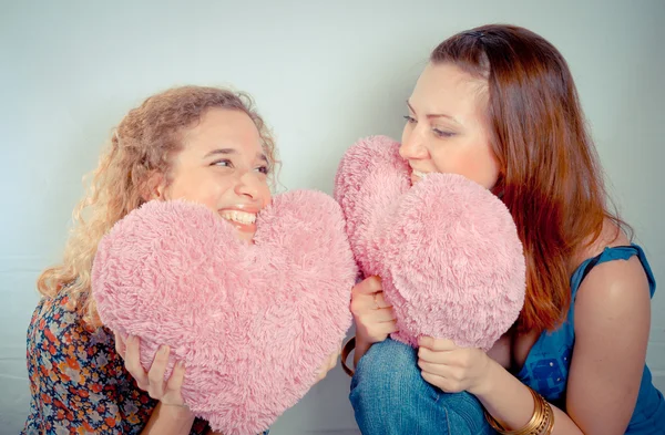 Two girls laughing and holding hearts — Stock Photo, Image