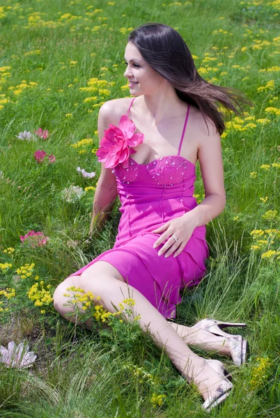 Giovane bella donna in abito rosa seduto su erba verde — Foto Stock