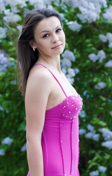 ライラック色の花の間で若くてきれいな女性 — ストック写真