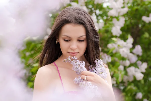 Jovem mulher bonita cheirando lilás rosa — Fotografia de Stock